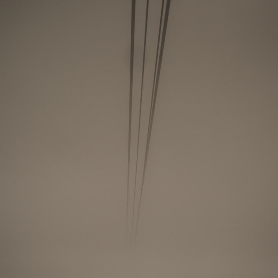 霧に沈んだ空を斜めに横切る数本の電線。ほかに何も写っていない