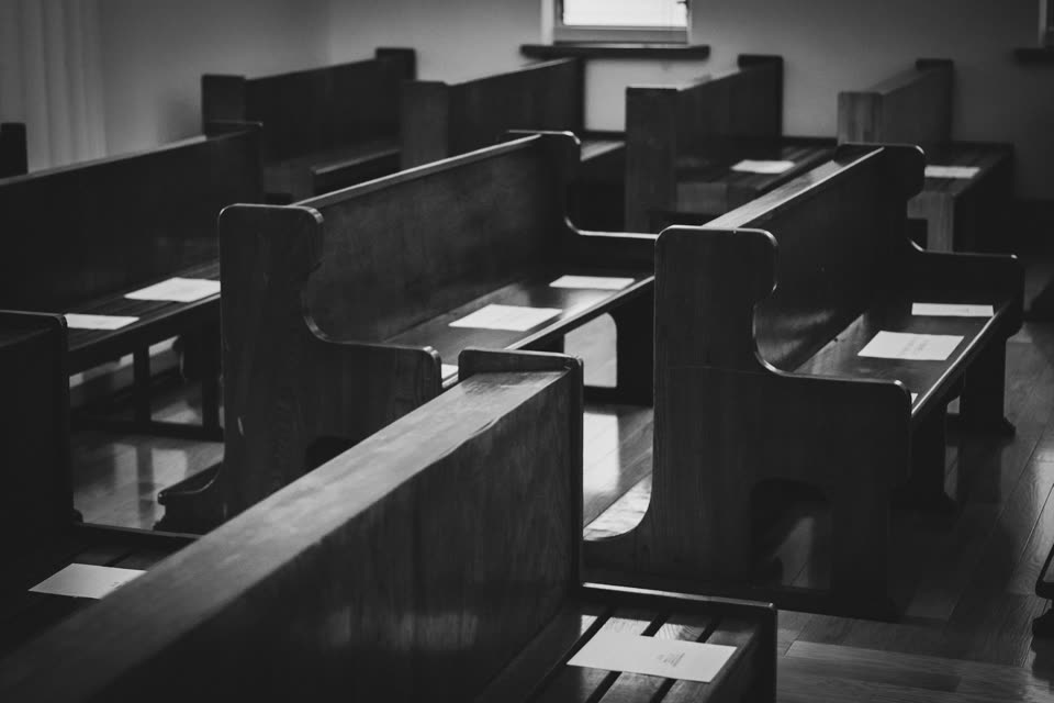 白黒。木製の長椅子が整然と並ぶ薄暗い室内。人はいない